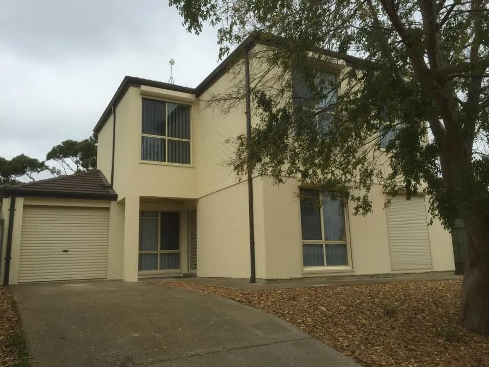 Street-front view of a completed two-storey home extension with an established garden