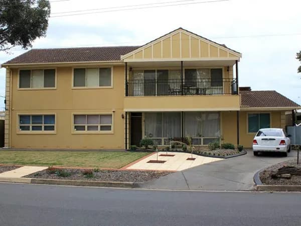 Large two-storey extension with a rendered facade, upstairs balcony and street parking