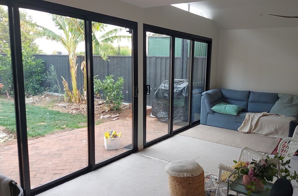 Living area of a completed home extension opening through full-height sliding doors onto a landscaped backyard